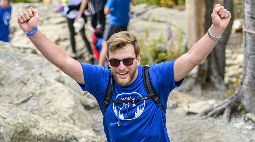 Man wearing a branded Climb t-shirt with his arms in the air triumphantly.