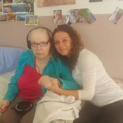 Naomi hugging Frances while sitting on her bed.