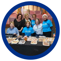 Group of 7 ladies behind a table featuring their baked goods
