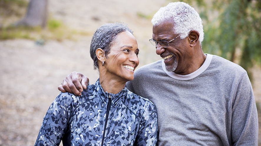 Senior couple looking at each other and smiling while on a walk outdoors.