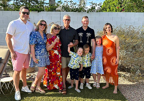 Kelly and Jeff Howsam with their family members. Everyone is wearing bright summer clothing.